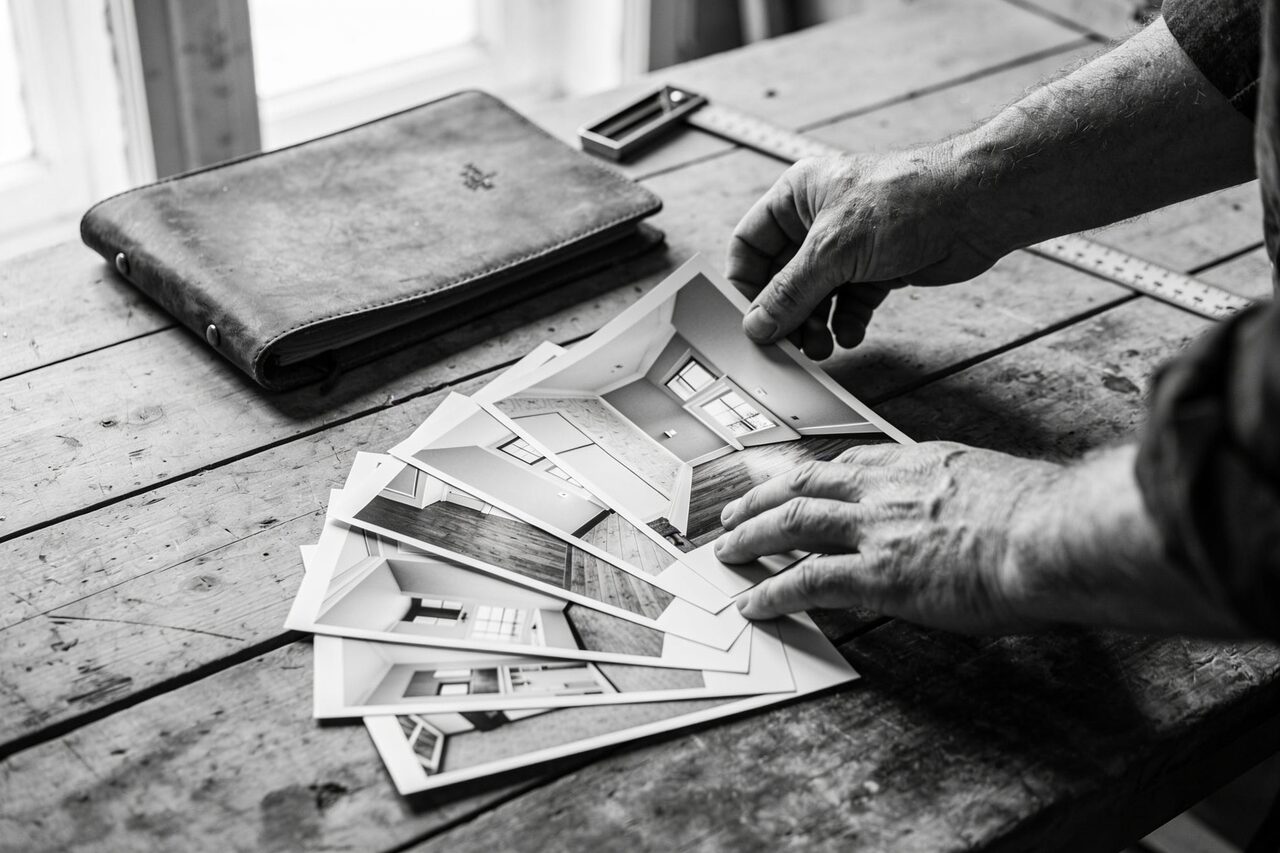 Handen waaieren uitgeprinte projectfoto's uit op een werkbank
